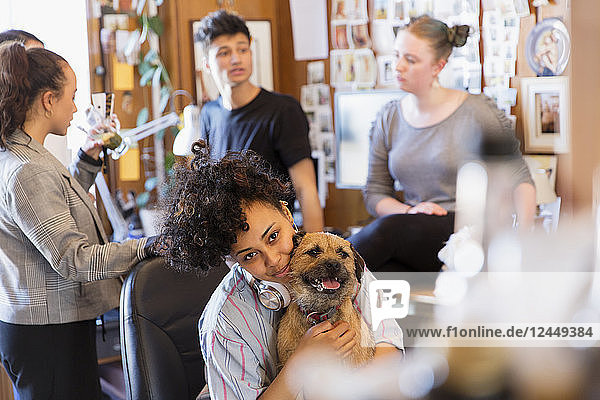 Portrait creative female designer with dog in office