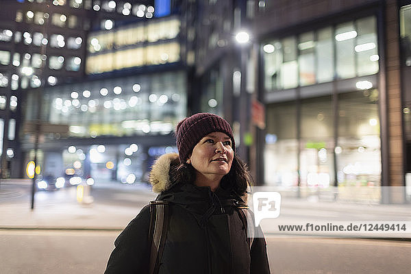 Woman in warm clothing walking on urban street at night