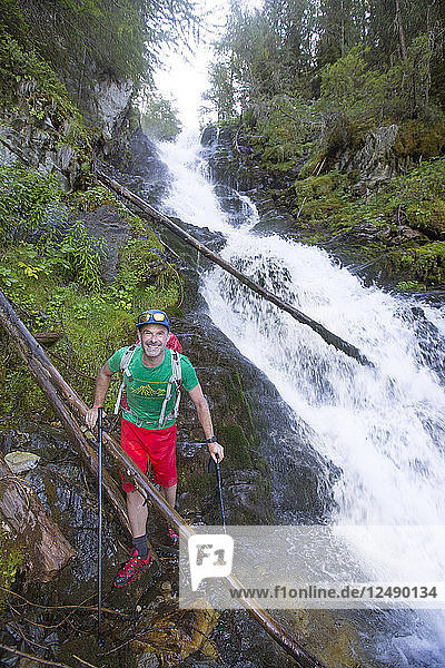 Ein männlicher Wanderer ist klatschnass  nachdem er einen Fluss mit Wasserfall im Val Danniviers überquert hat