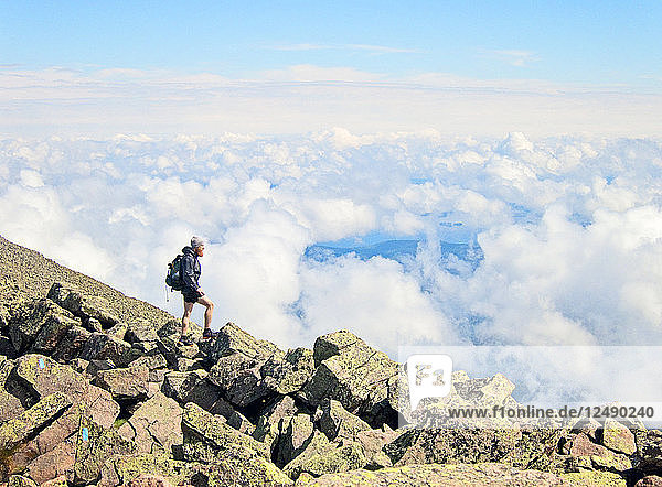 A hiker stands above the clouds near the summit of Mount Katahdin  Maine.