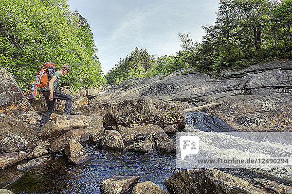 A Rock Climber Crossing A Stream In New York