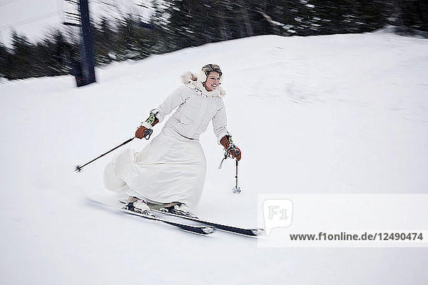 A woman skis down a mountain in a wedding dress after getting married.