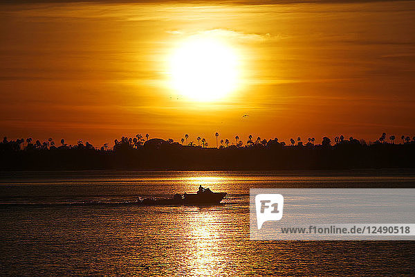 A boat glides across the water at sunset in Mission Bay in San Diego  CA.