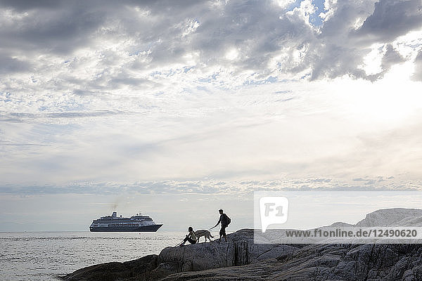 Entferntes Paar und Hund beobachten das Auslaufen des Kreuzfahrtschiffs