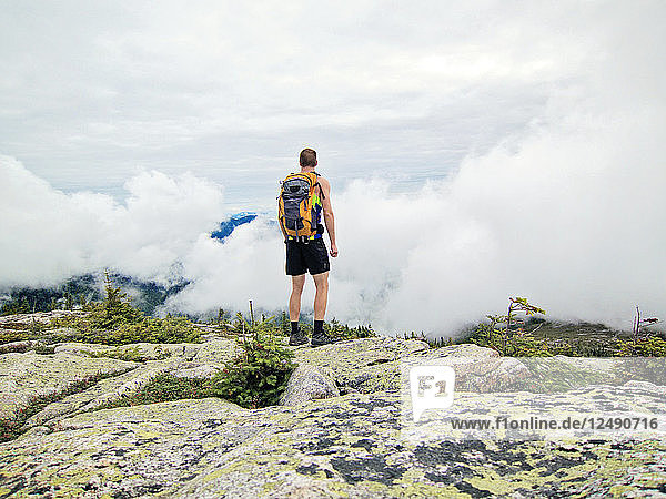 A man looks out over the clouds from the summit of Baldface Mountain  New Hampshire