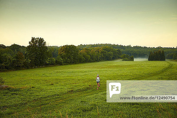 Eine Frau läuft durch ein Feld an einem nebligen Morgen