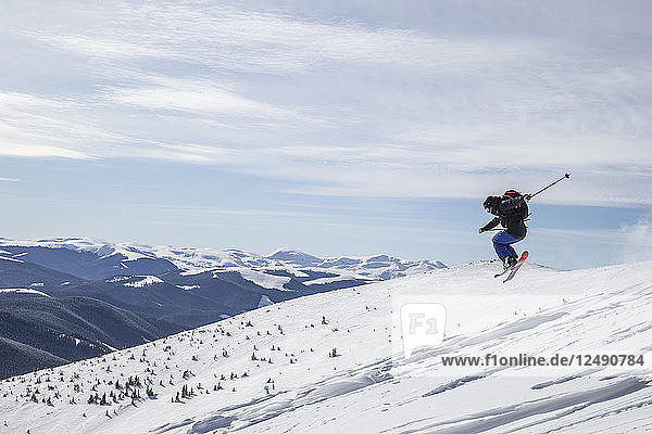 Skifahrer verdreht seine Skier in der rumänischen Wildnis in der Luft