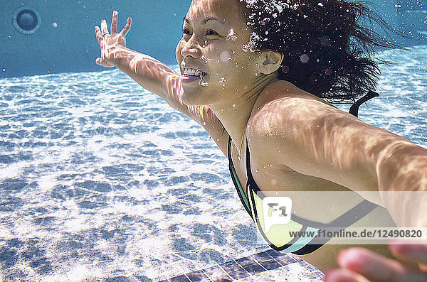Junge Frau schwimmt unter Wasser im Pool