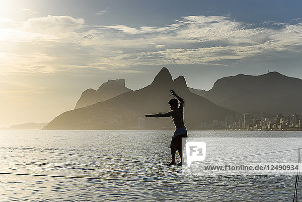 A Man Balances On A Slackline At Arpoador Beach During The Sunset  Rio De Janeiro  Brazil