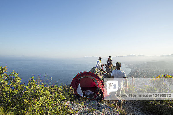 Familie mit Zelt am Hang über dem Meer