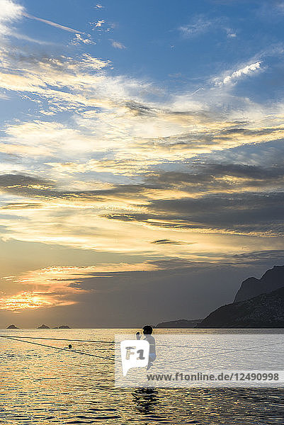 Ein Mann hockt auf einer Slackline am Strand von Arpoador während des Sonnenuntergangs  Rio De Janeiro  Brasilien