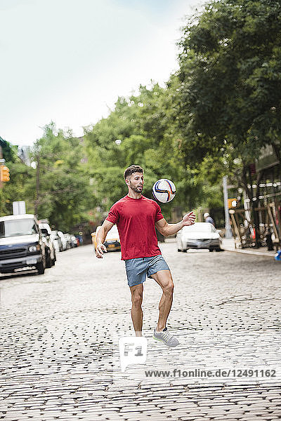 Athlete playing soccer on city streets