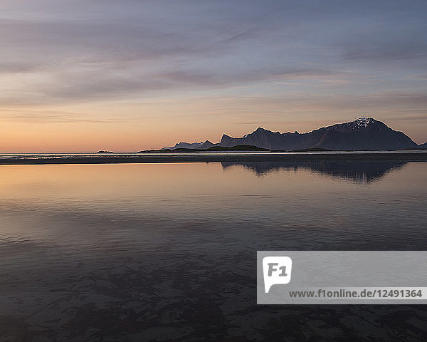 Midnight sun mountain reflection on Ytresand beach Moskenes??y Lofoten Islands Norway
