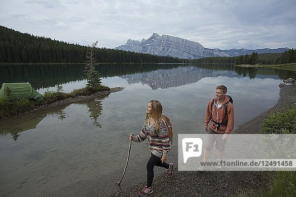 Young couple hikes along mountain lake