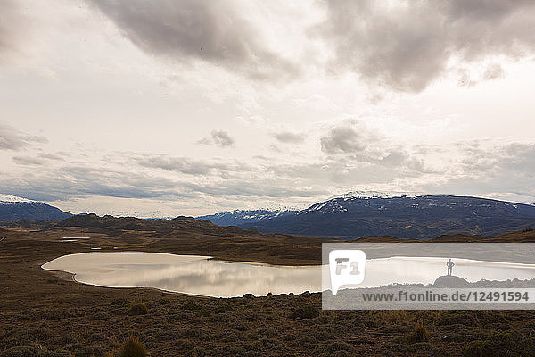 Mann  der inmitten einer weiten Landschaft mit Blick auf den See und die Berge in Patagonien  Chile steht