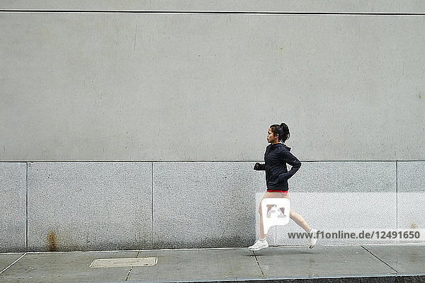 Eine junge asiatische Frau läuft auf dem Fußweg der Straße