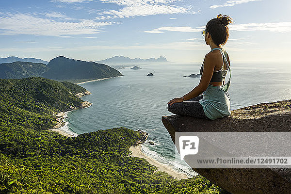 Woman sitting on the edge of the mountain in Pedra do Tel?©grafo  Barra de Guaratiba  west side of Rio de Janeiro  Brazil