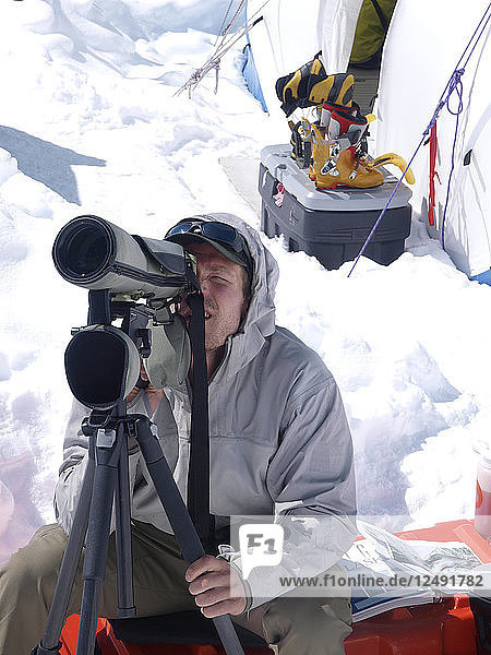 A mountain ranger is looking through the spotter during a search and rescue mission high on Denali in Alaska.