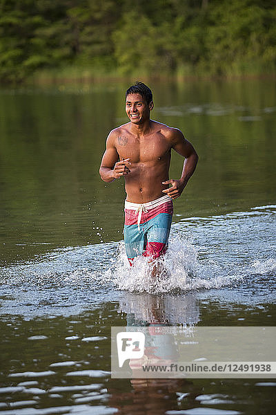 Junger glücklicher Mann läuft im Teich
