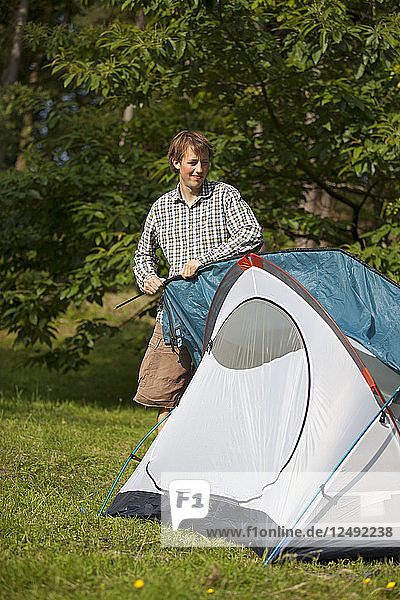 Camper legt letzte Hand an das Zelt auf dem Campingplatz