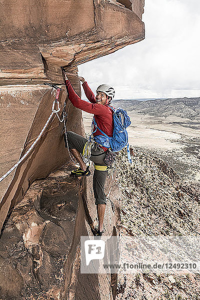 A man rock climbing a desert sandstone tower called Psycho Babble Tower in the Big Gypsum Valley near  Naturita  Colorado.