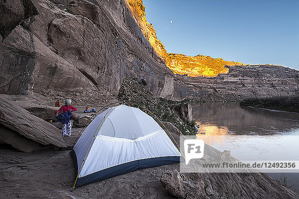 A young girl getting ready for bed in a tent while camping on sandstone along the Labyrinth Canyon section of the Green RIver  Green River  Utah.
