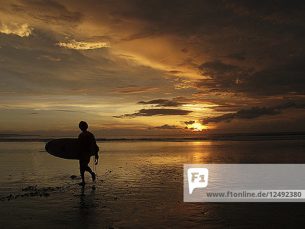 Ein Surfer  der am Ende des Tages zum Strand zurückkehrt. Ubud Kuta Strand Indonesien
