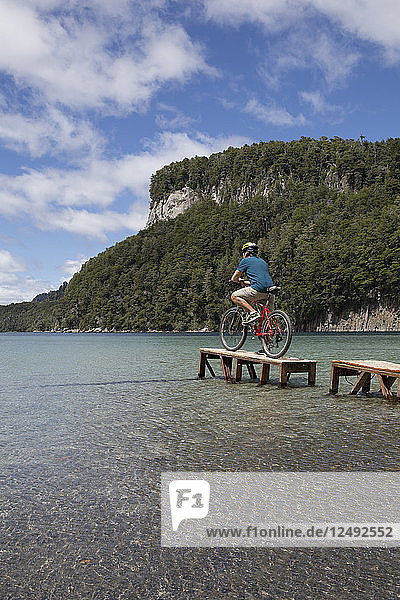 Fahrradfahrer betrachtet die Szene von einem kleinen Steg am Bergsee aus