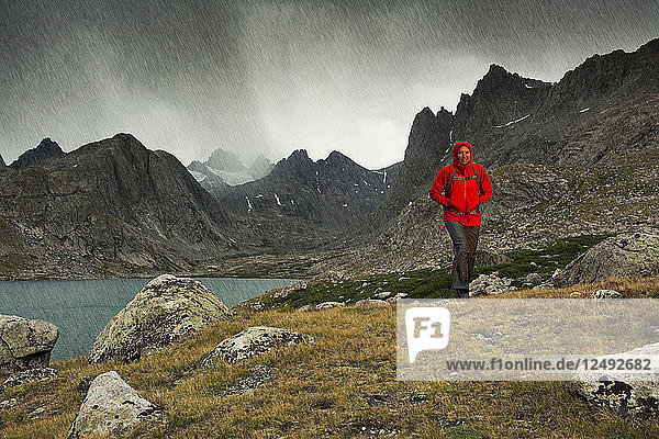 A woman hiking in heavy rain near the Upper Lake of Titcomb Basin in the Wind River Range  Bridger Teton National Forest  Pinedale  Wyoming.