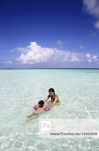 Mutter mit ihrem Kind spielen auf einem Sandstrand der Malediven in Gulhi