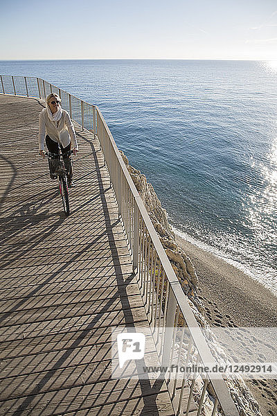 Erhöhte Perspektive einer Frau auf einem Fahrrad am Meer
