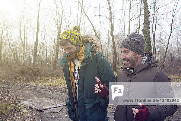 Two Male Friends Chatting While Walking In The Forest
