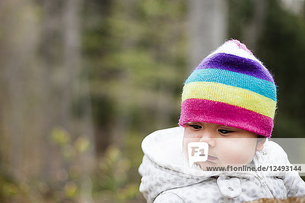 A 6 month old Japanese American baby girl wears a rainbow colored hat.