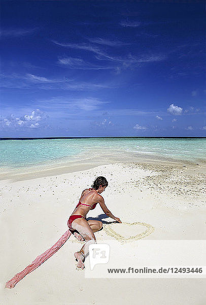 Frau Zeichnung Herz auf dem weißen Sandstrand auf den Malediven