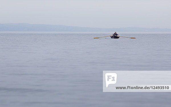 An einem nebligen Tag auf dem Skaneateles Lake rudert eine Frau ihr Adirondack-Führerboot in den Nebel.