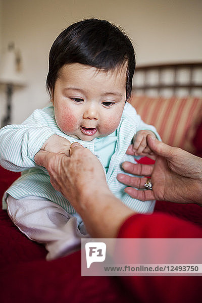 Eine Großmutter hält ihr 4 Monate altes japanisch-amerikanisches Mädchen im Arm.