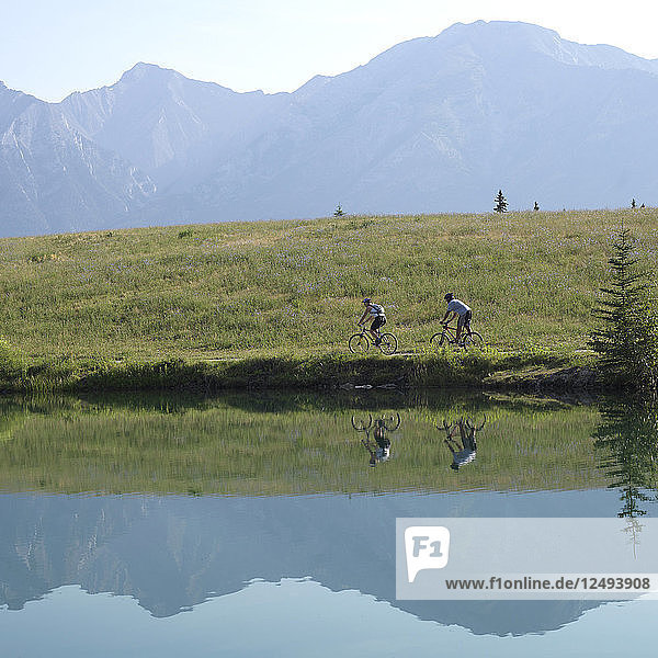 Zwei Mountainbiker auf dem Weg entlang des Bergsees