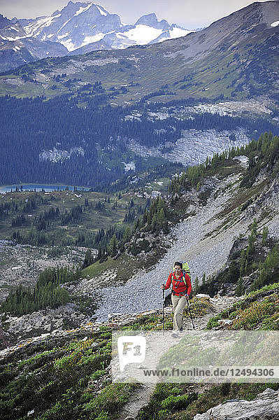 Woman hikes to the views of Glacier Peak Wilderness from Spider Gap on the Phelps Creek Trail  14.2-mile out-and-back  outside of Leavenworth  Washington September 2011. Phelps Creek leads to the base of Spider Glacier where you setup camp and hike to 7 100-foot Spider Gap. Camp has a bald eagle view of Spider Meadow below and craggy Seven Fingered Jack in the distance.
