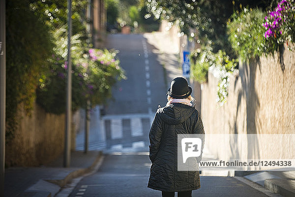 A girl walks down a colorful street on a sunny day in Barcelona  Spain.