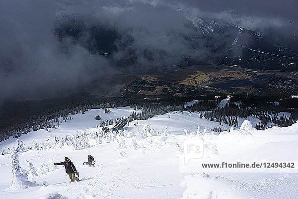 Zwei Snowboarder wandern aus den Toren des Skigebiets Revelstoke