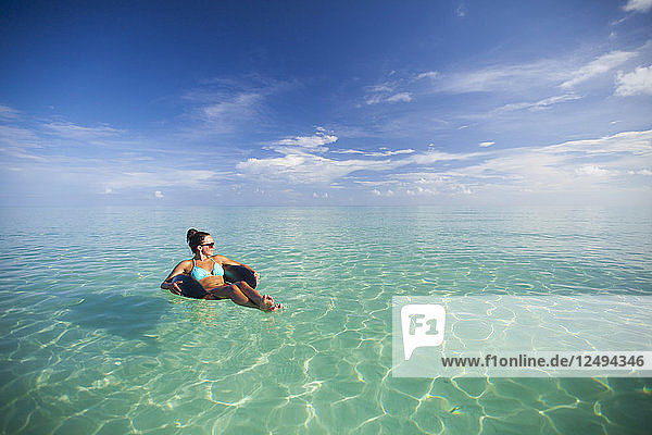A young woman floats on an inflatable tire in turquoise water while on vacation in Cayo Coco  Cuba.