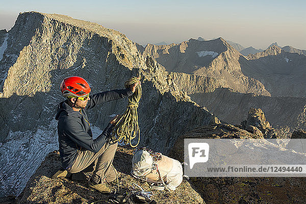 A man coiling a rope on the summit of Mount Mendel along the 8.5 mile Evolution Traverse  John Muir Wilderness  Kings Canyon National Park  Bishop  California.