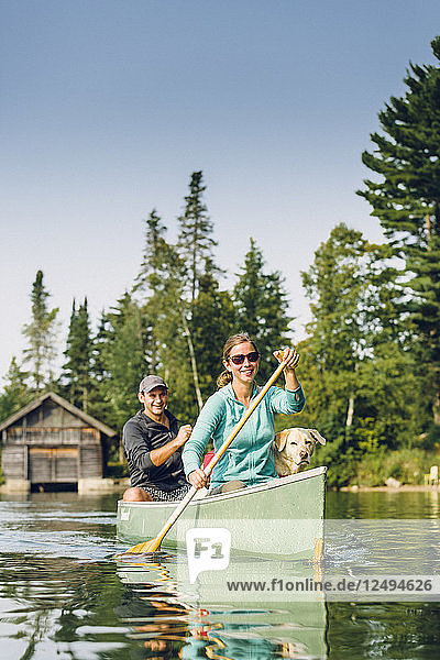 Lächelnder Mann und Frau Kanufahren mit ihrem Hund auf dem Kaspischen See