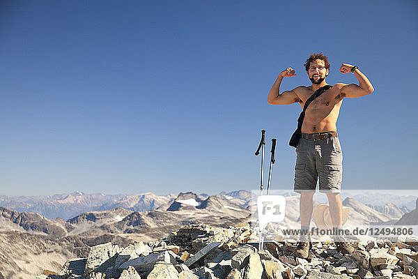 Ein Wanderer ohne Hemd lässt seine Muskeln spielen  nachdem er den Gipfel des Mount Cook im Garibaldi Provincial Park erreicht hat.
