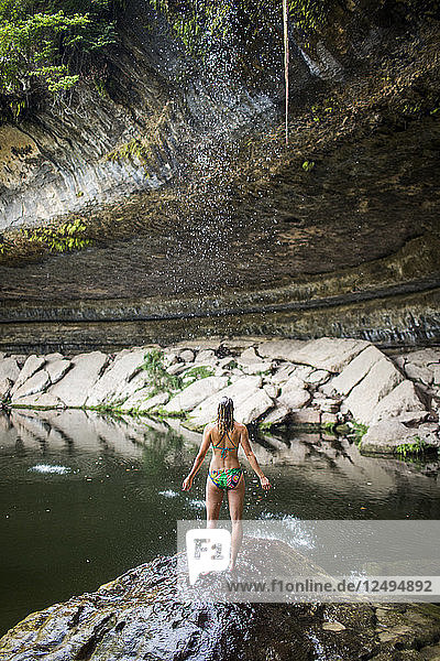 A young woman enjoys the Hamilton Pool near Wimberley  Texas on a hot day.