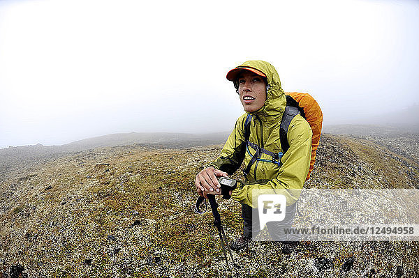 Eine Wanderin navigiert mit einem GPS-Gerät durch die Flanken des Homocide in der vorderen Bergkette der Chugach Mountains in Anchorage  Alaska  August 2011.