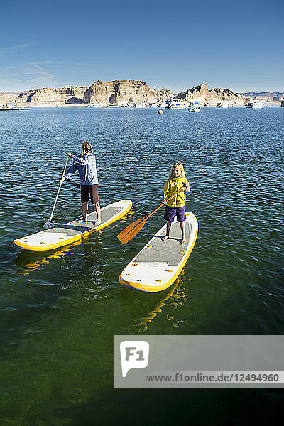 A mother and daughter paddleboarding on Lake Powell Wahweap Marina Glen Caynon National Recreation Area Page Arizona.