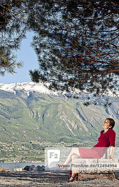 Frau sitzt am Ufer in Limone am Gardasee in Norditalien