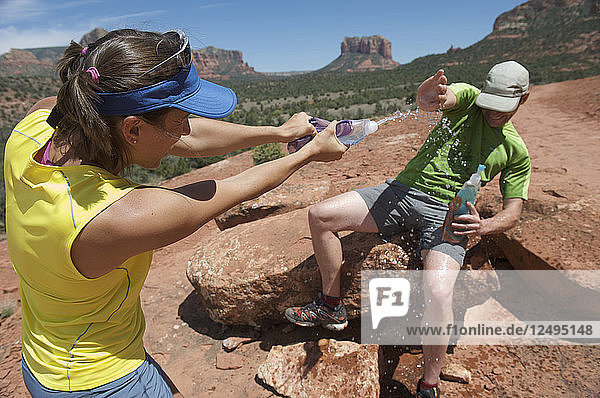 Ein Paar spielt mit Wasserflaschen auf dem Cathedral Rock Trail in Sedona  Arizona. Der Weg über glatten Sandstein führt zu einer beliebten Felsengruppe oberhalb von Sedona.