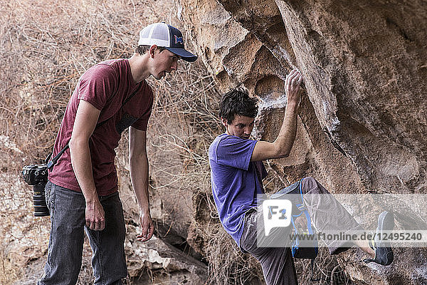 Rock climber figuring out the best way to climb the boulder during the Hueco Rock Rodeo competition in Hueco Tanks State Park  Texas